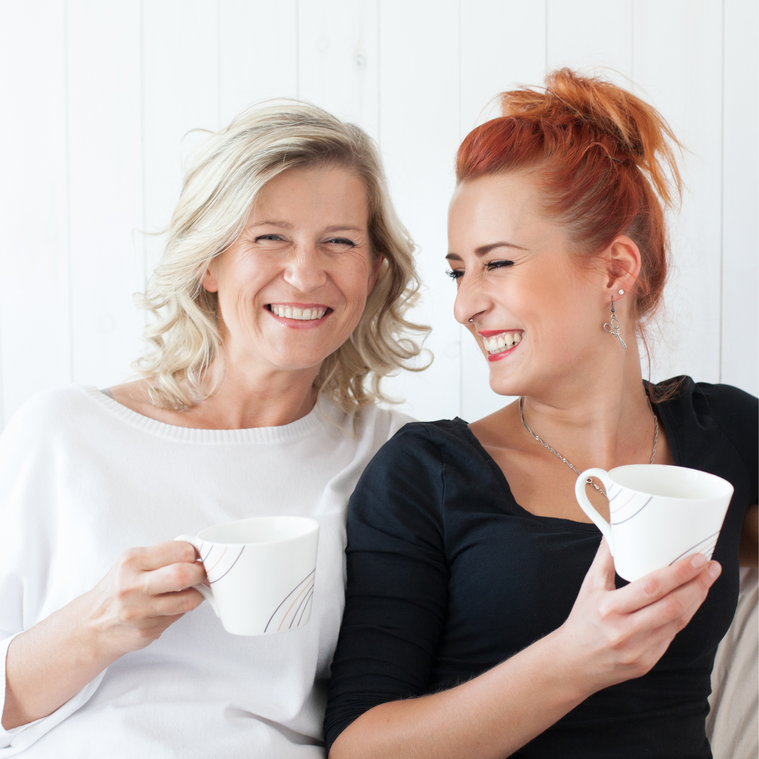 Mother and daughter sitting side-by-side smiling